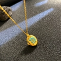 Goldenes Medaillon mit blauem Emaille-Muscheldesign auf schwarzer Steinoberfläche - Blaue Schnecke Ovaler Stil