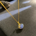 Halskette mit blauem Emaille-Muschelanhänger und goldenem Seestern auf dunklem Grund - Blaues Muschel-Stil