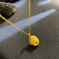 Goldene ovale Käfer-Halskette mit grüner Emaille auf dunklem, strukturiertem Hintergrund - Gelber Käfer Ovaler Stil