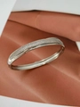 Détail d'un bracelet jonc argenté serti de zircons avec un design élégant et chevauchant - Bracelet jonc / Or blanc