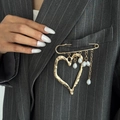 Broche cœur doré style lave avec perles baroques sur la poche d'un blazer gris chic - Doré