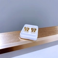 Detailansicht der goldenen Schleifenohrringe mit Reliefstruktur und funkelndem Zirkon-Zentrum - Schleifen-Textur / Goldener Schmetterling