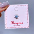 Detail eines Schneeflocken-Ohrrings mit blauem Zirkonia auf einer rosa Karte - Blauer Zirkonia Blume