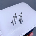 Detailaufnahme von Titanstahl Kettenohrringen mit blauen Zirkonia auf einer Box - Dreifach-Zirkon-Quaste / Silber
