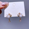 Elegante goldene Tropfenohrringe mit weißen Perlen und Zirkonia auf einer Displaykarte - Gold