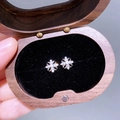 Nahaufnahme von Zirkon-Kreuz-Iris-Ohrringen in einer Schmuckschatulle aus Walnussholz - Chrome Kreuz