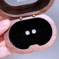 Makroaufnahme von Zirkonia-Ohrsteckern in einer hochwertigen Schmuckbox aus Holz - Baguette Zirkon
