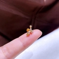 Makroansicht goldener Blumen-Ohrstecker mit Zirkonia-Steinen auf einer Fingerspitze - Gold Schmetterling Reihe Zirkonia