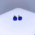 Nahaufnahme der blauen Kristallohrstecker mit Goldschliff auf weißem Schmuckkästchen - Vergoldet Dunkelblau