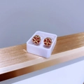 Nahaufnahme goldener hohler Herz-Blumen-Ohrstecker mit rotem Edelstein in weißer Box - Gold-Roter Zirkonia