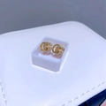 Detailaufnahme goldener Ohrstecker mit ineinandergreifendem G-Design und Zirkonia-Besatz - Buchstabe G