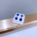 Detail shot of blue crystal pavé ball earrings in a white box on a golden edge - 5mm Royal Blue Zirconia
