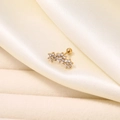 Makro-Detail des vergoldeten gebogenen Ohrsteckers mit drei funkelnden Zirkonia-Blüten - Goldene Zirkonia-Blumenreihe (Einzelstück)