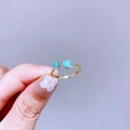Detailansicht eines verstellbaren Goldrings mit blauen Herzsteinen am Modellfinger - Doppelherz Blaue Dekorsteine (L34R4600)