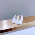 Gros plan de boucles d'oreilles en acier doré avec triple fleurs en zircone étincelante - Rangée de Fleurs en Zirconium Dorée