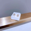 Détail de clous d'oreilles dorés avec zircone rectangulaire dans une petite boîte blanche - Zirconium Géométrique Doré