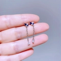 Nahaufnahme asymmetrischer Schmetterlings-Ohrringe mit blauen Zirkon-Steinen aus Silbermetall - Silber Blau Schmetterling Quaste