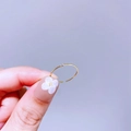 Detailansicht eines schmalen goldenen Rings mit klarem Zirkonia auf lila Hintergrund - Japanischer Minimalistischer Mikroedelstein (E56R3488)