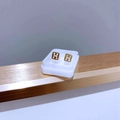 Nahaufnahme goldener Titanstahl H-Form Ohrstecker mit Schraubverschluss im Display - Gold Quadrat H