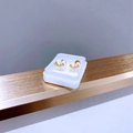 Detailaufnahme von goldfarbenen Titanstahl-Ohrsteckern im Smile-Design auf einem Display - Gold Buchstabe T Lächeln