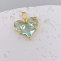 Macro-opname van een gouden hartvormige hanger met drie gefacetteerde lichtblauwe zirkonia stenen - Drie-Steen Lichtblauw Hart (H)
