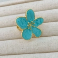 Macro shot of blue enamel camellia flower ring with adjustable gold metal band - Pine Blue
