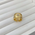 Dettaglio di anello largo dorato con texture spazzolata, fiori traforati e piccoli diamanti - Anello
