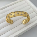 Dettaglio macro del bracciale rigido dorato spazzolato con stelle e cristalli incastonati - Bracciale rigido