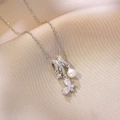 Detail der silbernen Schmetterlingskette mit Zirkonia und Perle auf Seidenhintergrund - Silber - Schmetterling Künstliche Perle Halskette