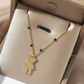 Detailed shot of golden bear pendant with white zircons and black beads on a gold necklace - Micro-Inlaid Zirconia Bear Style (T0569)