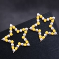 Boucles d'oreilles étoiles dorées ajourées avec perles blanches et jaunes sur fond noir - Jaune