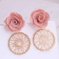 Detail von rosa Stoffrosen und goldenen gewebten runden Boho-Ohrhängern aus Metall - Rosa