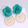 Detail of teal gauze rose and gold wire-wrapped circular drop earrings on a stand - Green