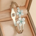 Close-up of stainless steel bangle with dual flower charms and green stones on silk - Double Flower Design / Silver