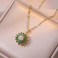 Detailweergave van een gouden zonnebloemhanger met groene blaadjes en kristallen aan de ketting - Smaragd zonnebloem roterende ketting