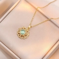 Detailed view of a gold sunburst necklace with a green gemstone and zircon in a gift box - Sunflower Pendant Necklace (X0052)
