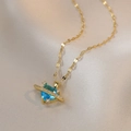 Collier doré avec pendentif cœur en zircon bleu sur un tissu élégant en soie champagne - Collier Planète Bleue Dorée