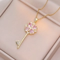 Collier clé doré avec pendentif trèfle en cœur rose dans un écrin à bijoux beige - Or-Zircone Rose