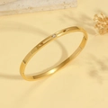 Detalle macro de un brazalete dorado con ranura rectangular y circonita transparente - Estilo Minimalista de Circonita Única Dorada (TT0888)