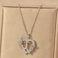 Close-up of heart-shaped letter T pendant with green zircon and floral details - Hollow Heart Letter T Necklace / Silver