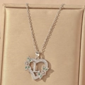 Detailed macro view of heart pendant with letter L, green gems and pavé zircons - Hollow Heart Letter L Necklace / Silver