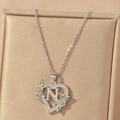 Close-up of silver heart pendant with letter N, green gems and white zircons - Hollow Heart Letter N Necklace / Silver