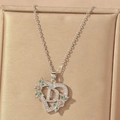Macro view of silver heart pendant with letter D and green gemstones in a jewelry box - Hollow Heart Letter D Necklace / Silver