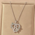 Close-up of heart-shaped letter B pendant necklace with green gems and zircons - Hollow Heart Letter B Necklace / Silver