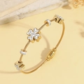 Dettaglio macro del bracciale rigido a spirale dorato con tre ciondoli a quadrifoglio - Stile con ciondolo a trifoglio ricoperto di diamanti / Stile Oro (TT1004)