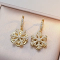 Elegante goldene Schneeflocken-Ohrringe mit glitzernden Zirkonia auf Schmuckbox - Goldene Schneeflocke Ohrringe