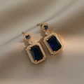 Vue macro détaillée de boucles d'oreilles zircon bleu sur satin champagne - Bleu (E0090)