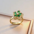 Bague fleur dorée avec pierres précieuses vertes sur une boîte à bijoux de luxe - Bague Verte