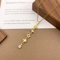 Gold pendant necklace with star, saturn, and heart zircon elements on wood background - XL5129 Planet Clover Tassel Necklace / Gold