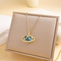 Golden necklace featuring a blue faceted heart pendant with a Saturn-style metal ring - Blue Heart Planet Necklace (Gold Chain)